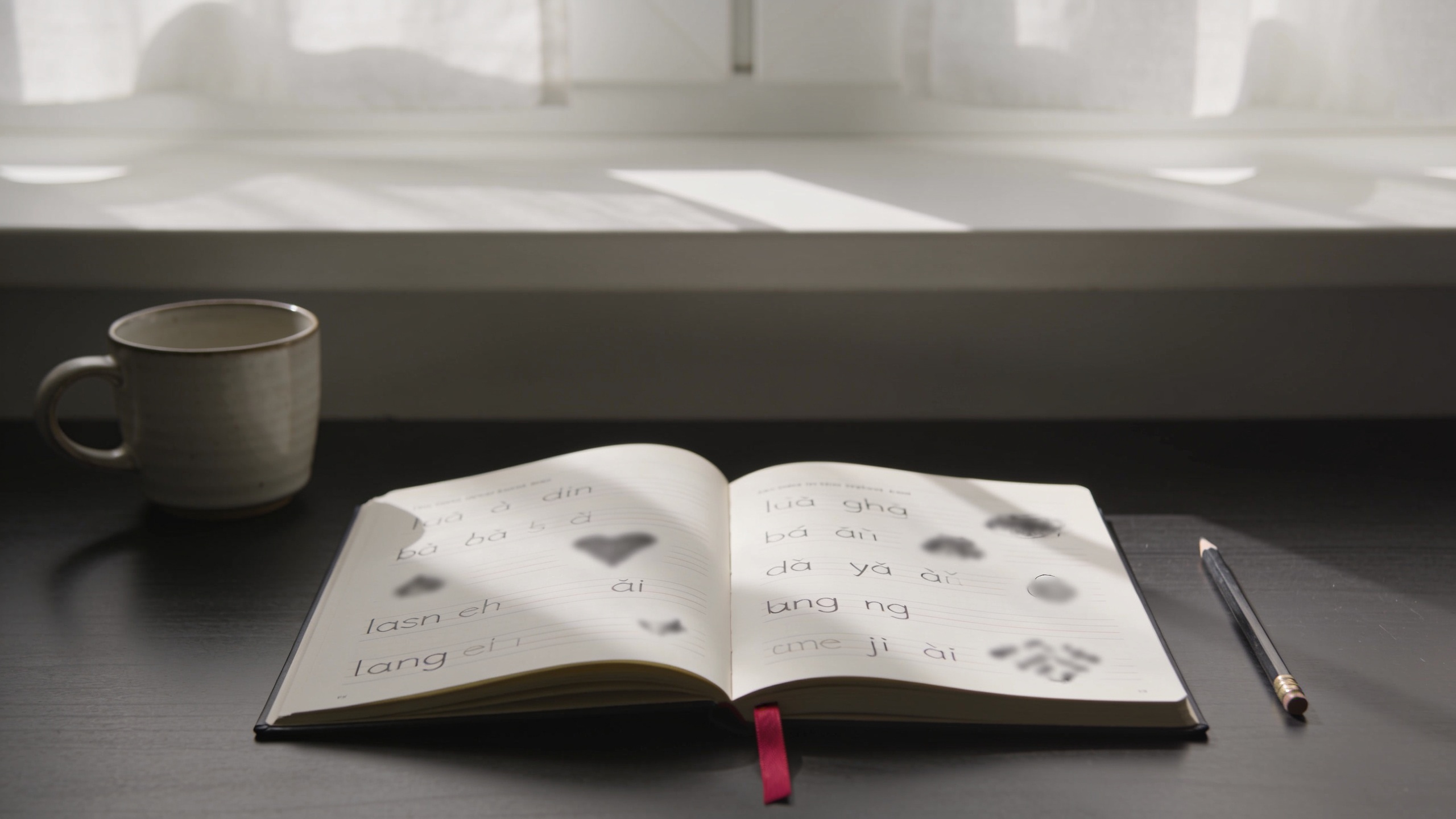 Editorial desk with an open Polish pronunciation notebook, warm daylight, and a crimson bookmark